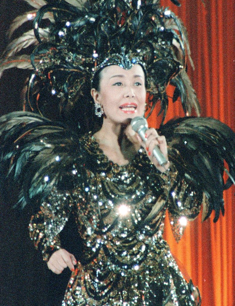 Misora Hibari chantant avec ferveur dans un costume évoquant un phénix, conçu par Mori Hanae. En avril 1988, au Tokyo Dome (Kyôdô)