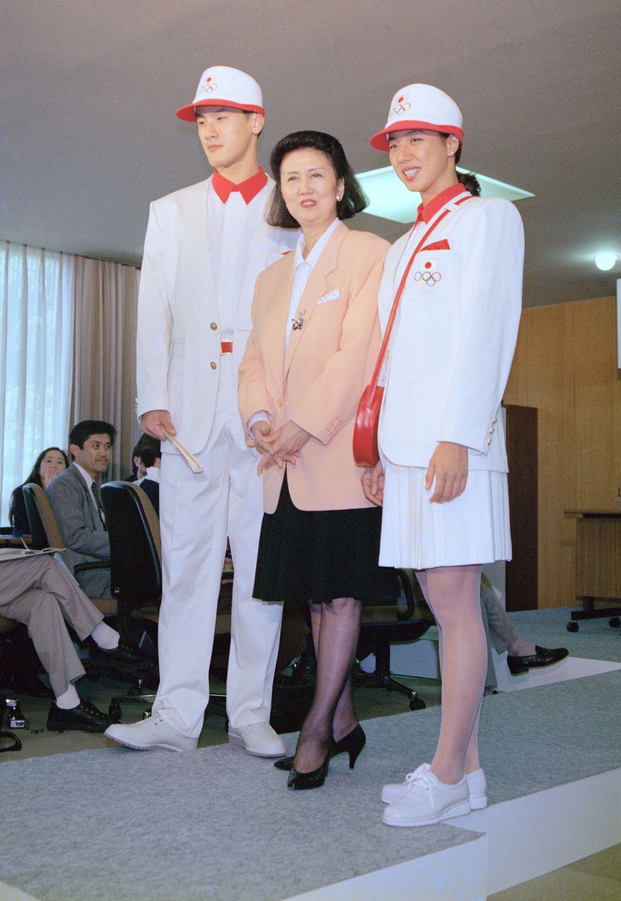 Mori Hanae (au centre) présente l’uniforme officiel de la délégation japonaise pour les Jeux olympiques de 1992. Les modèles sont le volleyeur Nakagaichi Yûichi (à gauche) et la nageuse de natation synchronisée Kotani Mikako, en 1992, au Kishi Memorial Gymnasium, à Tokyo. (Jiji)