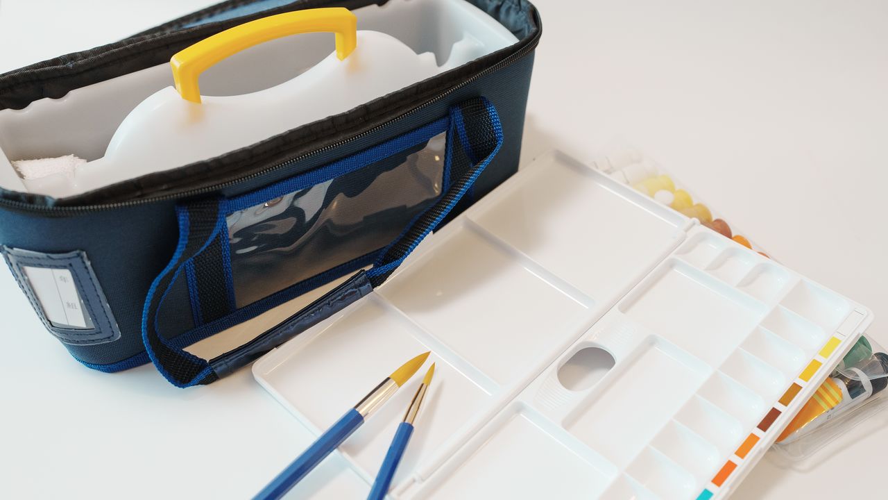 Un coffret d'aquarelle comprend des pinceaux, une bassine, des godets de peinture et une palette. (© Pixta)