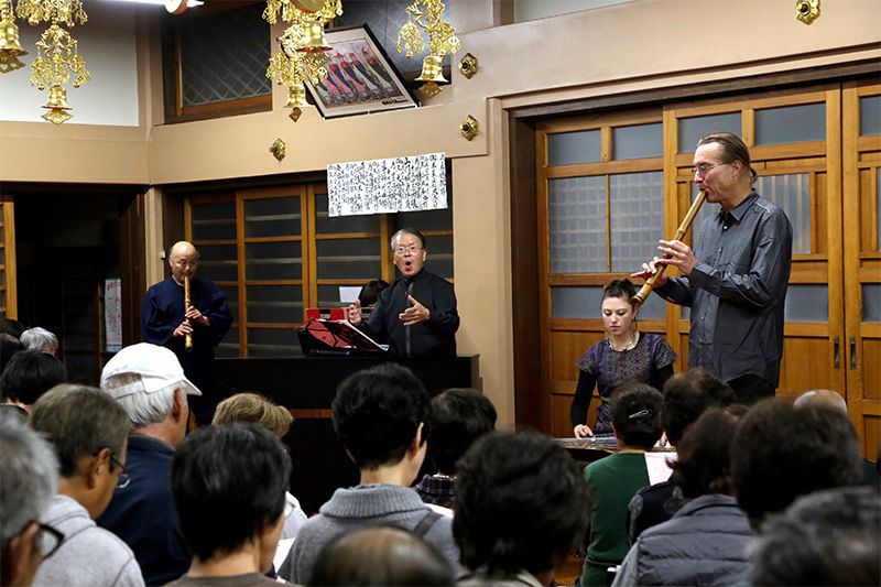 Bruce Huebner (à droite) joue de la flûte shakuhachi lors d'une représentation dans la ville de Kôri, dans la préfecture de Fukushima. Dans le public, des personnes évacuées de la ville voisine de Namie.