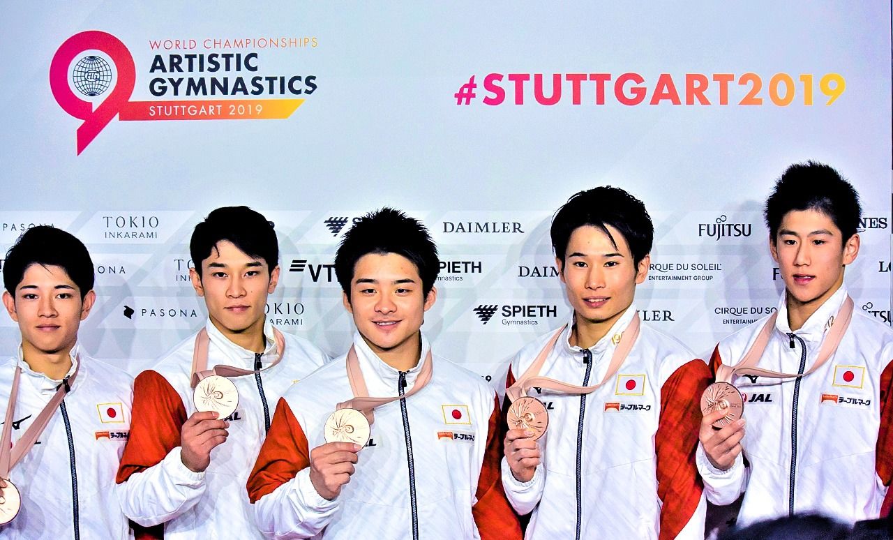 Hashimoto Daiki (à droite) montrant fièrement sa médaille de bronze, en compagnie d’autres de l'équipe japonaise de gymnastique aux Championnats du monde de Stuttgart (avec l’autorisation de Yanai Yumiko).