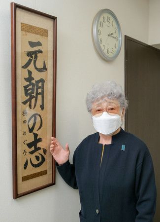 Yokota Sakie devant une calligraphie réalisée par sa fille Megumi lorsqu'elle était écolière