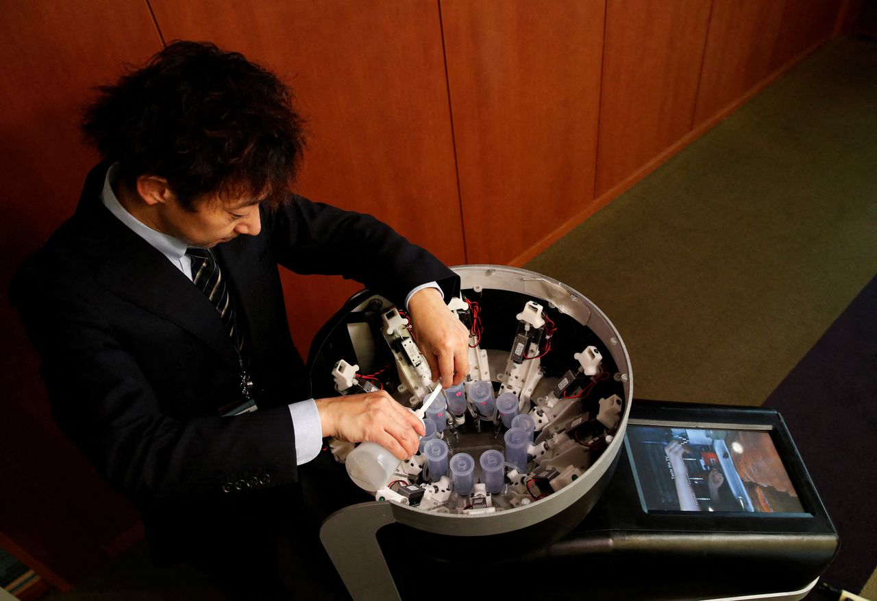 Le professeur Miyashita de l’Université de Meiji remplit les réservoirs à saveurs pour présenter TTTV. (REUTERS/Kim Kyung-Hoon)