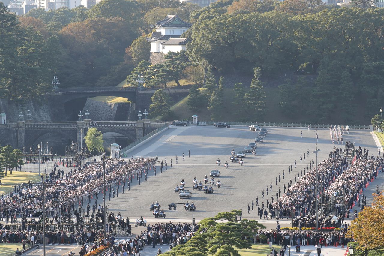 La procession traverse la grande place devant le palais impérial. Elle est composée de 50 voitures  et se prolonge sur 400 mètres. La limousine du couple impérial est en tête.