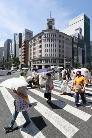 Des Japonais se protégeant sous des ombrelles, à Ginza (Tokyo), le 27 juin après-midi.