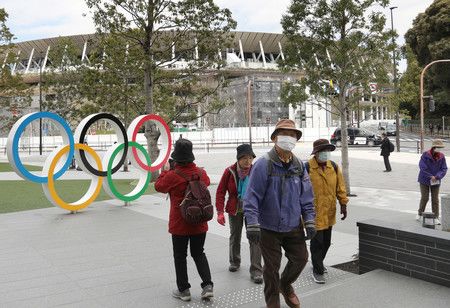 Le Stade Olympique de Tokyo, et les passants portant un masque.