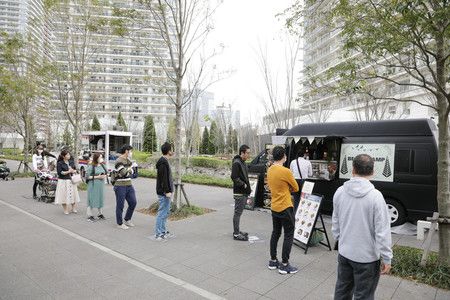 Dans une zone résidentielle de Tokyo, les clients des food truck font la queue en respectant une certaine distance.