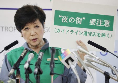 Koike Yuriko brandit une pancarte « Vigilance nécessaire dans les quartiers de distractions nocturnes », lors de sa conférence de presse le 2 juillet.