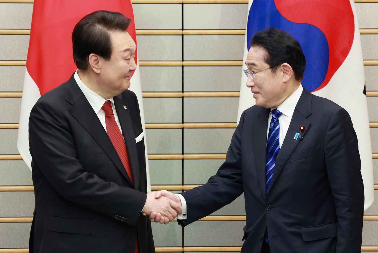 Le président sud-coréen Yoon Seok-youl (à gauche) et le Premier ministre Kishida se serrant la main au début de leur rencontre, le 16 mars à la résidence du Premier ministre (Jiji Press).