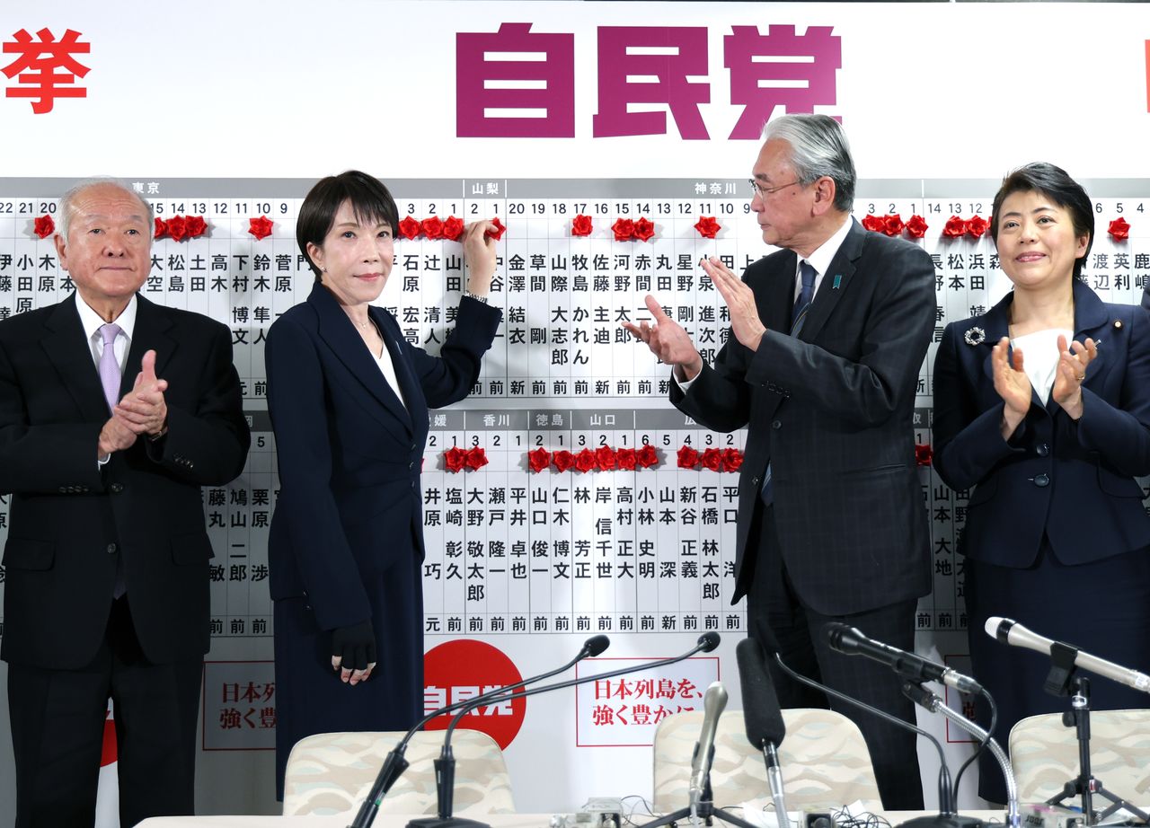La Première ministre Takaichi Sanae posant des fleurs au-dessus des noms des candidats victorieux de son parti, au siège du PLD dans l'arrondissement de Chiyoda (Tokyo), dans la nuit du 8 février 2026. (Jiji)