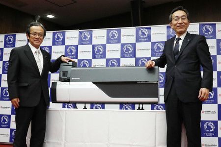 Le PDG de Shimidzu, Ueda Teruhisa (à gauche), et le président de l'Université du Tôhoku, Ôno Hideo, présentent le nouvel appareil de détection du coronavirus (le 16 octobre, à Sendai)