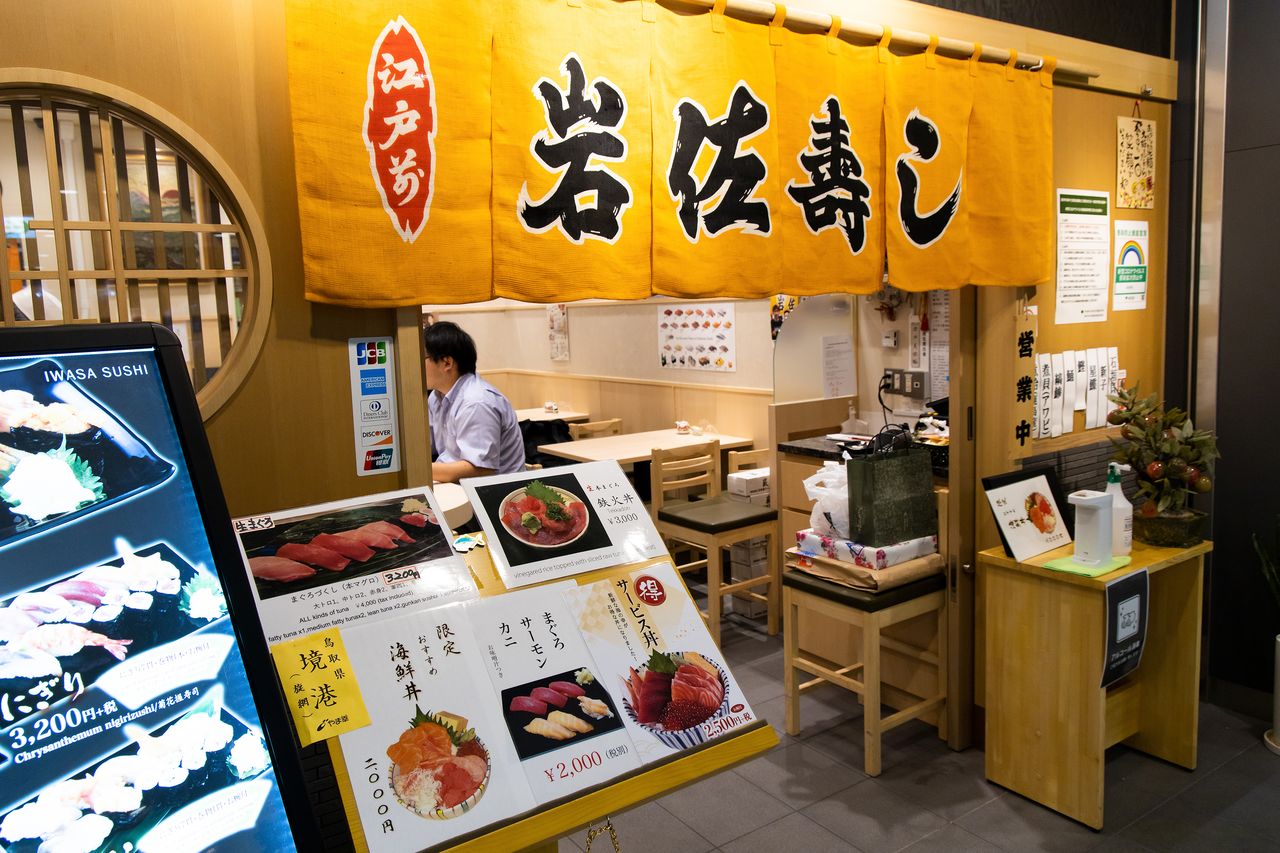 岩佐壽司在店門口宣傳鮭魚菜單（nippon.com編輯部）