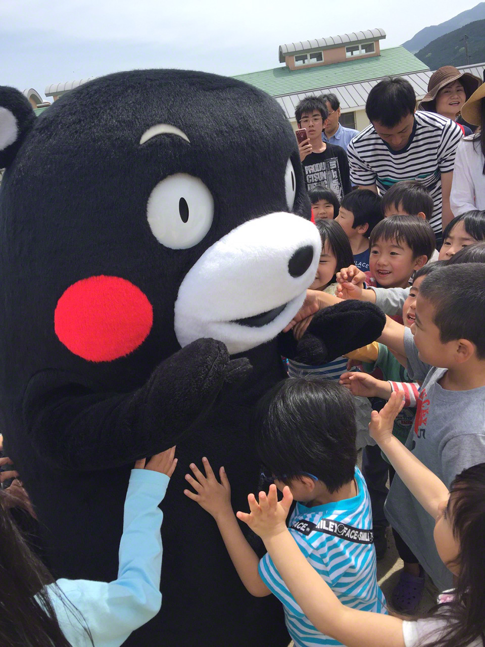 訪問熊本地震受災地西原村的西原托兒所後，被孩子們熱情圍著一頓揉搓的熊本熊，2016年5月5日（熊本縣）