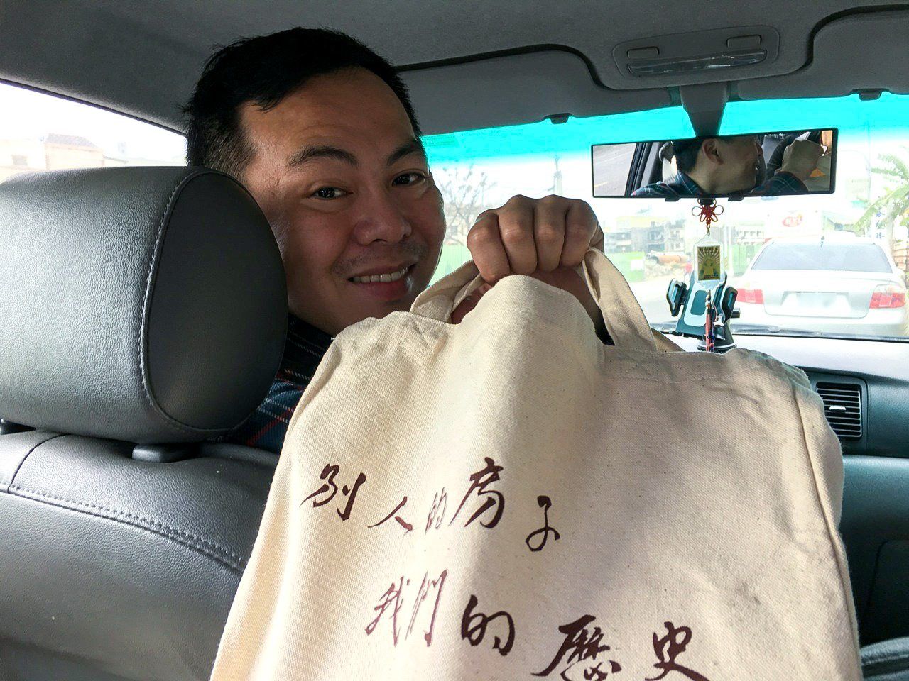 張敬業先生手持「鹿港囝仔」製作的環保提袋，上面印製「別人的房子，我們的歴史」的文字（渡邊義孝先生提供）