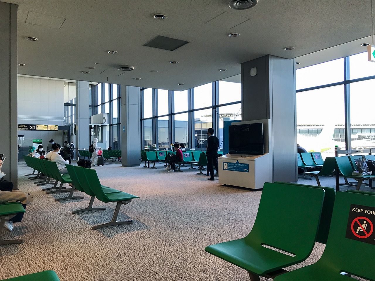 搭機前的日本成田機場登機口，有不少乘客避免在飛機上感染，穿上全套隔離衣。（筆者拍攝）