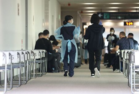 接受抗原檢查後於入國者檢疫待機區內等待的相關人士（中央）＝6月、千葉成田機場