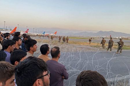 16日、聚集在阿富汗首都喀布爾機場的阿富汗人（左）與警戒中的美軍（AFP時事）