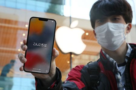 正式開始販售的美國蘋果公司智慧型手機「iPhone」新一代機種「13」,圖為手持新手機的男性=24日上午、東京都千代田區「APPLE丸之內」