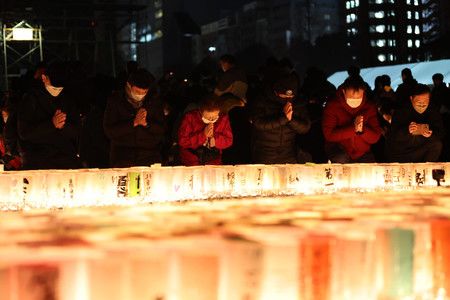 迎接阪神大地震27週年之際、在發生時刻默禱的人們＝17日上午5點46分、神戸市中央區東遊園地