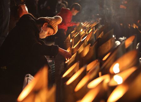 迎接阪神大地震27週年之際、追悼集會上點亮竹燈籠的女性＝17日上午、神戸市中央區東遊園地