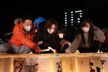 迎接阪神大地震27週年之際、出席追悼儀式上點亮紙燈籠一家人＝17日上午、神戸市中央區東遊園地