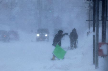 大風雪中，進行除雪作業的人們＝21日下午、北海道岩内町