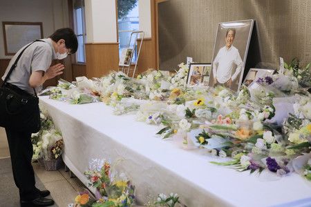 前首相安倍晉三的母校清溪學園的花壇前，一名男子合十祈福＝15日上午，東京武藏野市