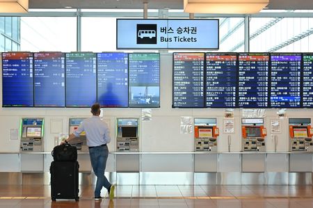 一名外國男子在東京羽田機場國際航廈看巴士時刻表＝10月11日（AFP時事）