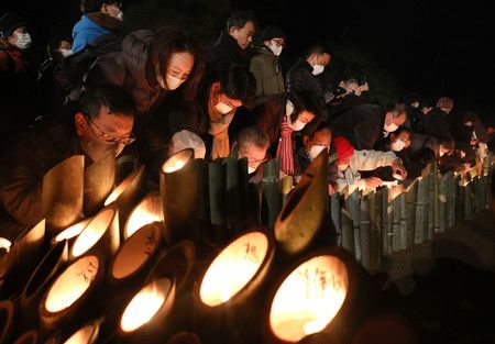 悼念阪神大地震的罹難者，點亮竹燈籠的人們＝17日上午、神戸市中央區的東遊園地