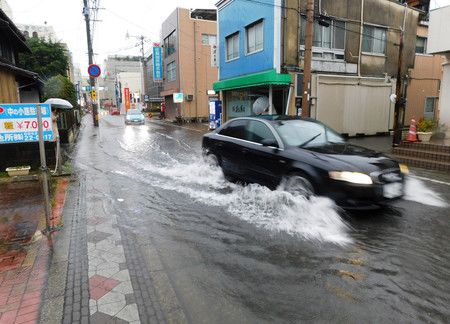 大雨後水灌入道路下行駛的汽車。（6日午後、佐賀市）