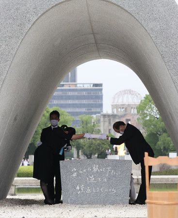 和平紀念儀式上，將原爆者死没者名簿奉納在慰霊紀念碑上的廣島市長松井一實（右）與家屬代表（8月6日上午於廣島市中區的和平紀念公園）