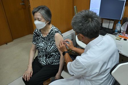 接種秋季新冠疫苗的女性（左）＝20日上午、東京都港區