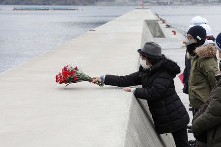 在海上保安廳出發前往失蹤者前，持著花束等待出發的成田博美（左）＝2月11日、宮城縣女川町