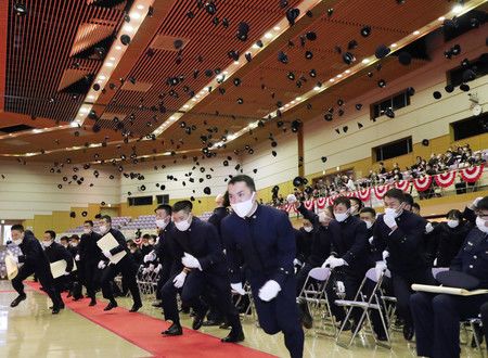 畢業典禮結束、將帽子投向高空奔跑而出的防衛大學畢業生＝21日上午、神奈川縣横須賀市