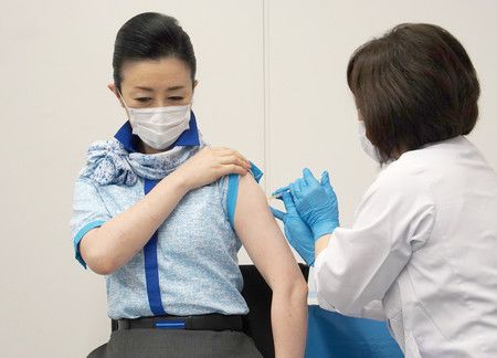 接受新型冠狀病毒疫苗施打的全日本空輸客艙機組員（左）＝13日上午、東京都大田區羽田機場