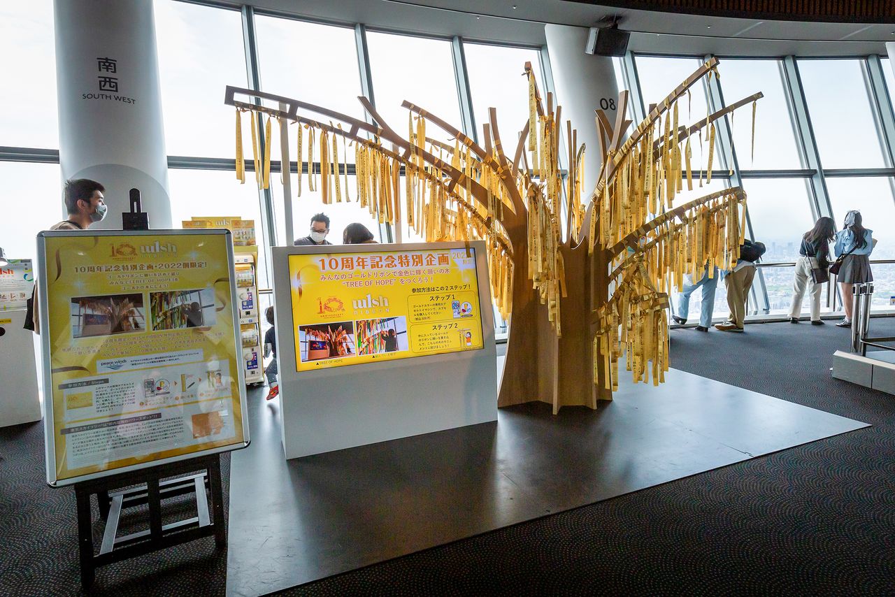 地上350メートルの天望デッキに設置してある10周年記念企画の「W1SH RIBBON」。日本一高い建造物・スカイツリーはパワースポットとしても人気なので、ゴールドのリボンに願いを込めて木に結ぼう