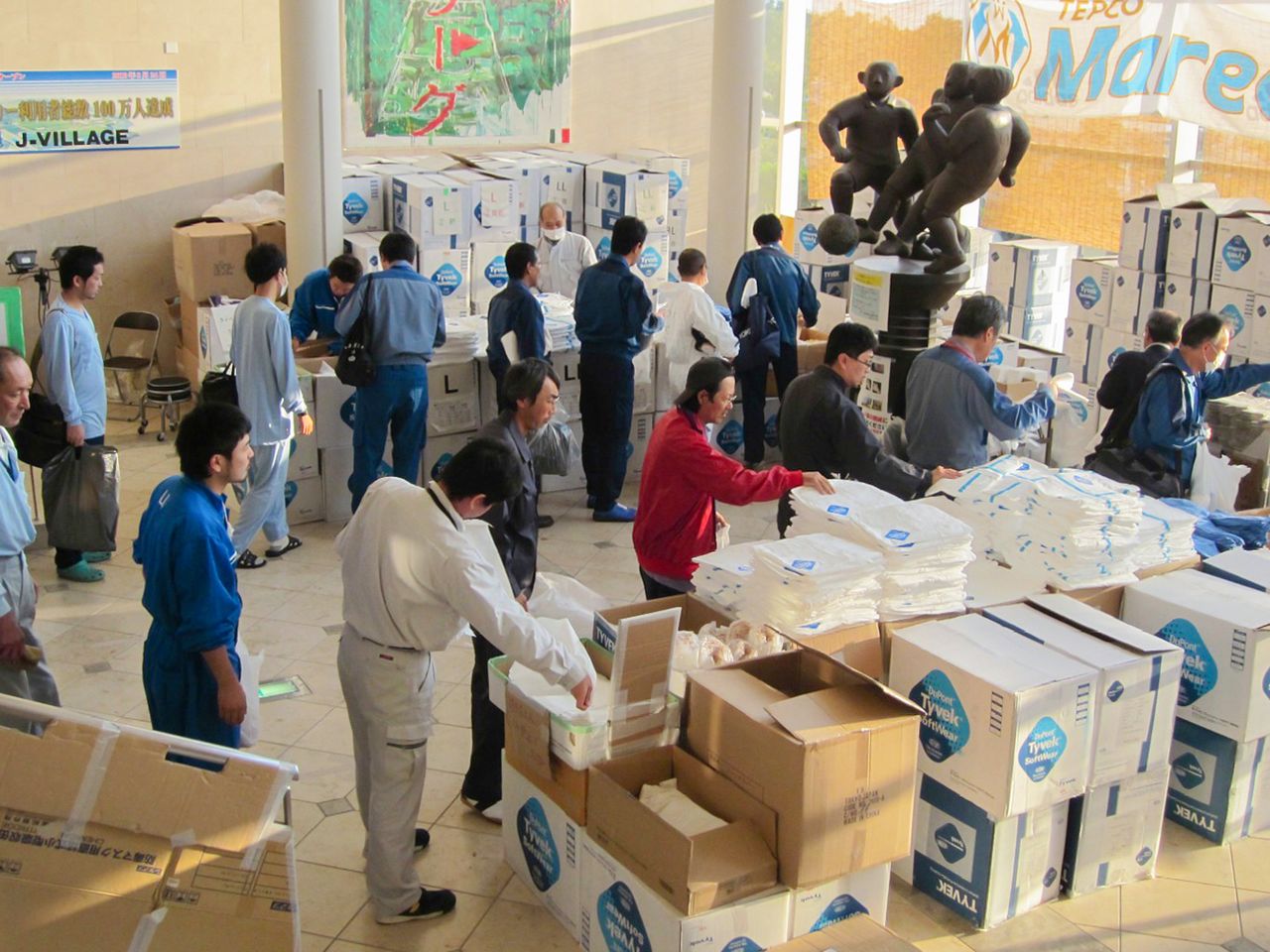 ホテル棟のエントランスホールに積まれた防護服を受け取る作業員たち(2011年10月、提供:東京電力 時事)