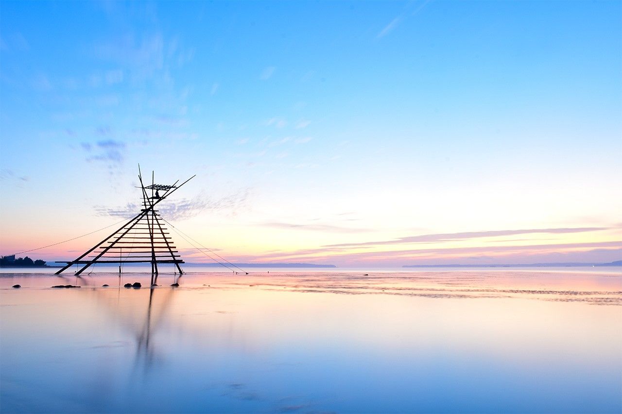 鏡のような海面に立つ「ボラ待ちやぐら」。ボラが網に入るのをやぐらの上で待ち続ける伝統漁法だ