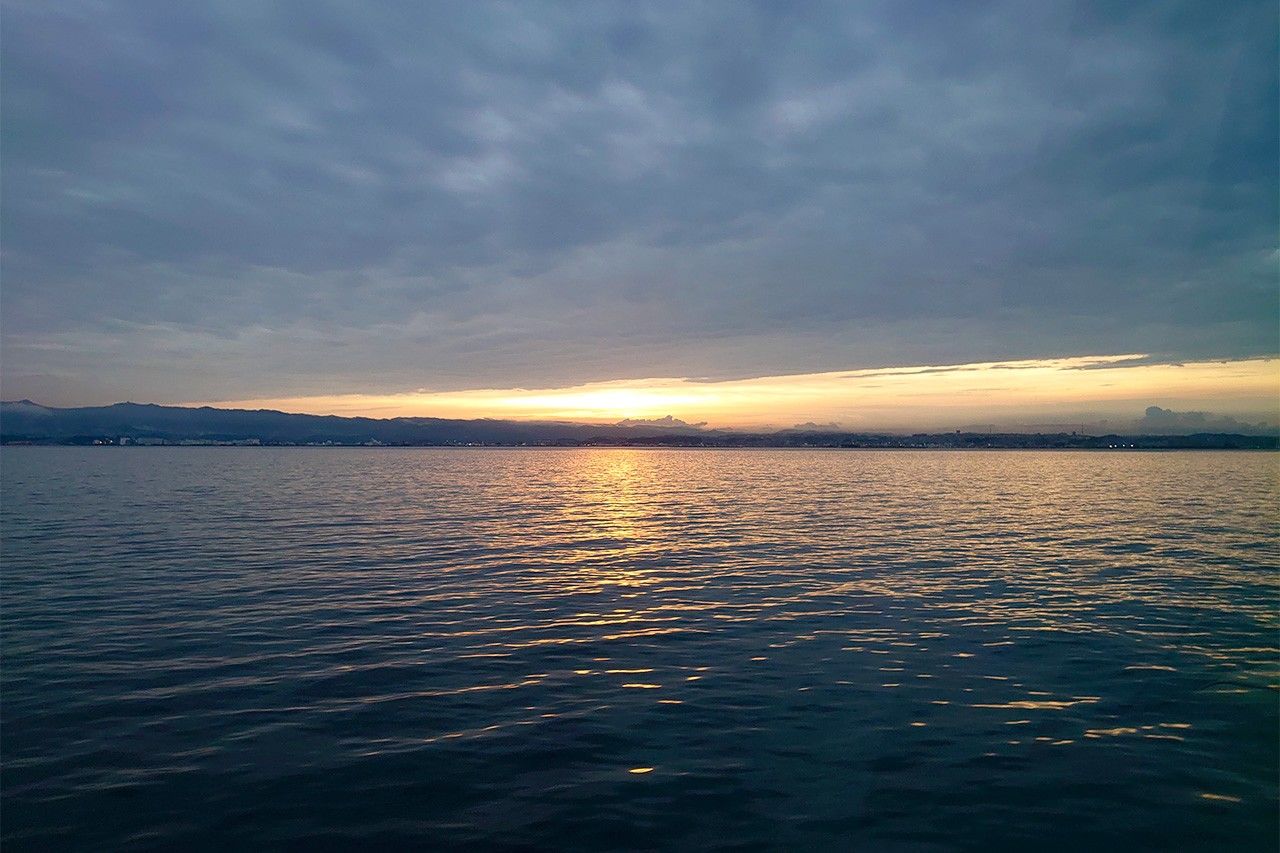 厚い雲の層の向こう側に、金色の夕陽が輝いていた ©李琴峰