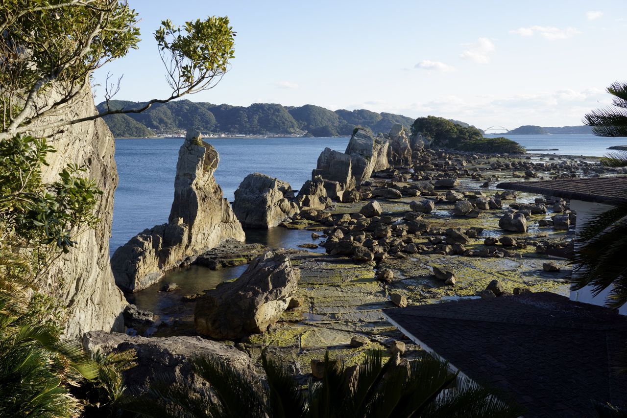 一列に並ぶ岩の奥、緑に覆われた弁天島(中央右)には鳥居と祠がある 撮影=大坂 寛