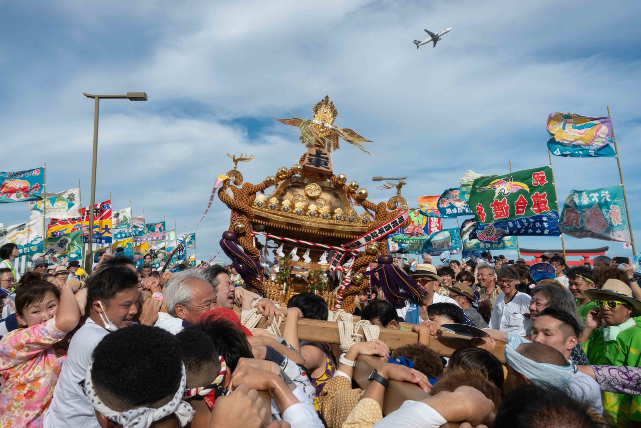 羽田神社夏季例大祭。大漁旗がはためく上空を飛行機が飛び交う=初沢亜利撮影