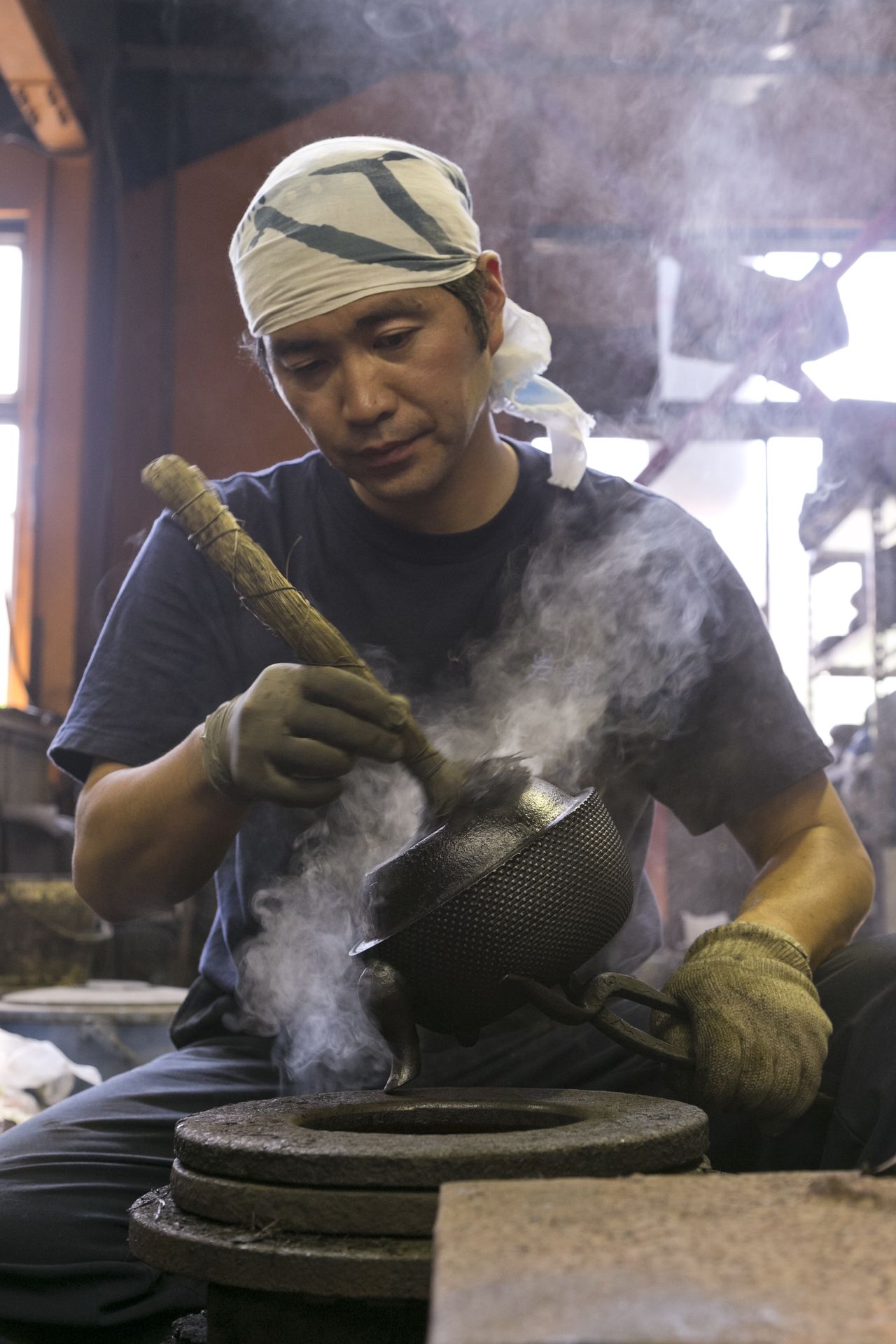 工房での着色作業。鉄瓶を約250℃に加熱し、その表面に漆を焼き付ける/写真提供:岩鋳