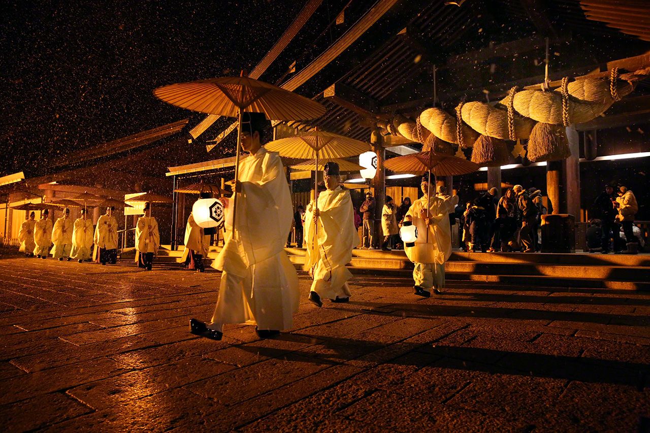 和傘を手に拝殿前を進む神職の姿は日本ならではの風景。