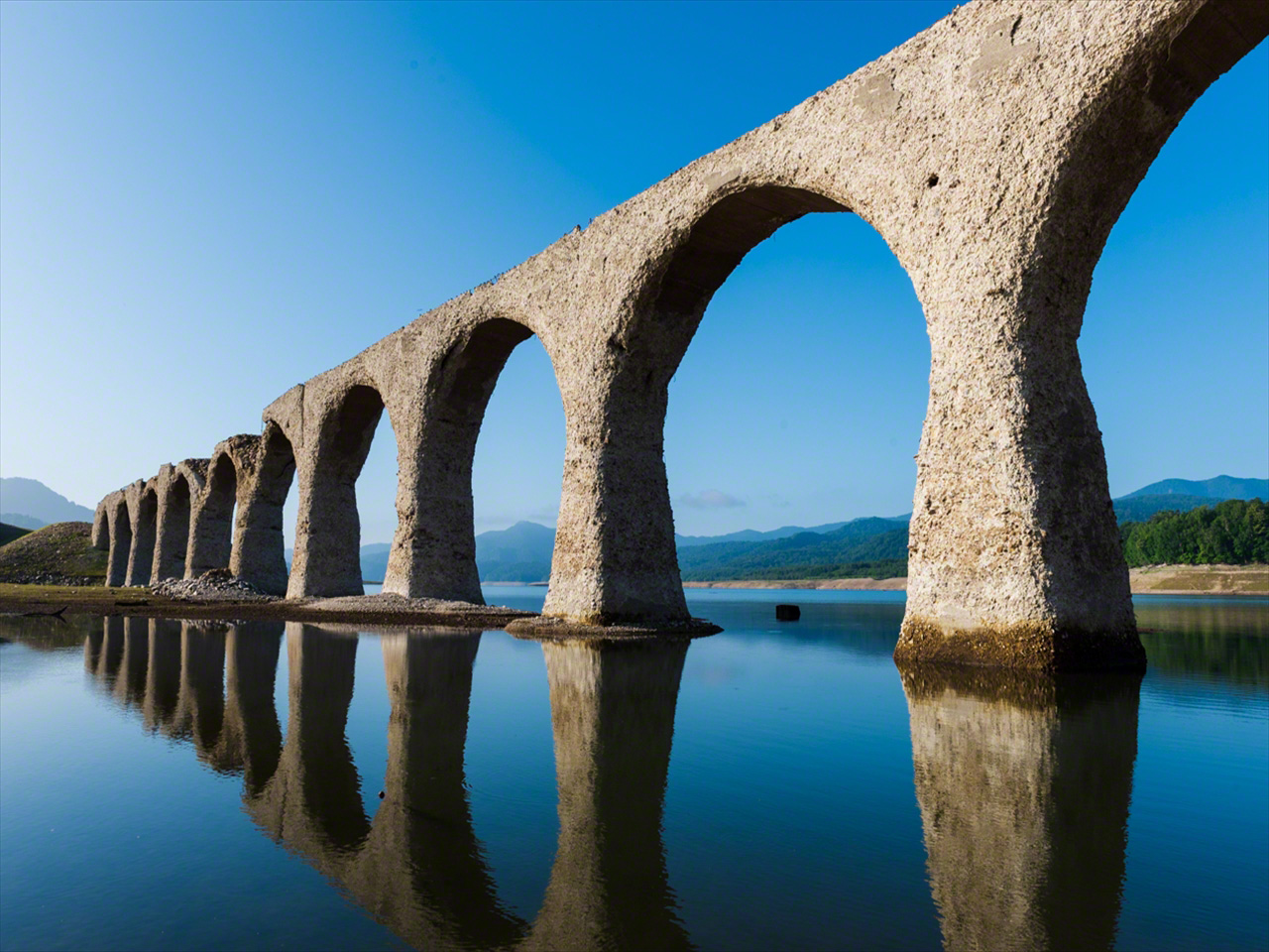 風のない朝、水面にアーチ橋が映る。「めがね橋」とも称される所以だ。7月