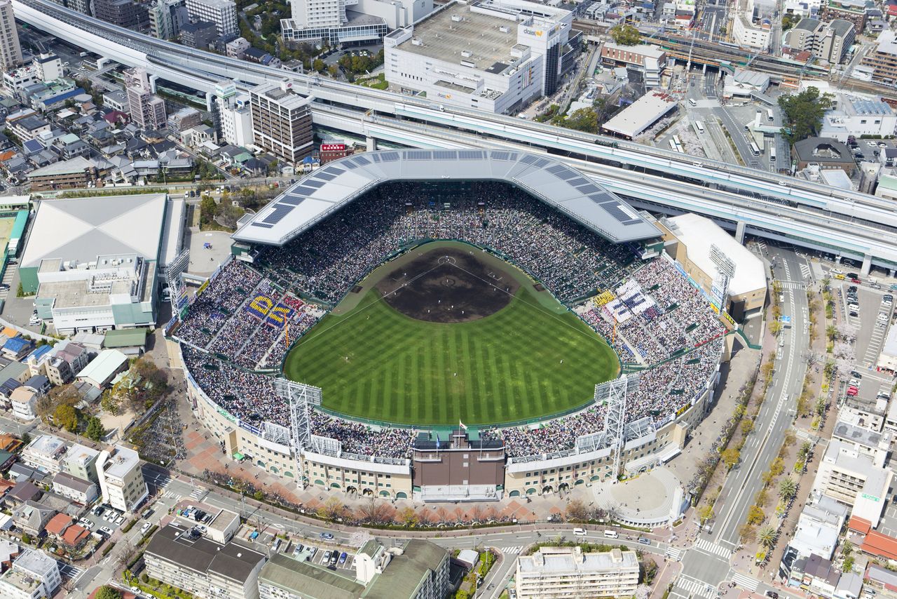 甲子園球場の全景。“甲子園名物”である、内野の一部座席を覆う大屋根「銀傘(ぎんさん)」はガルバリウム鋼板製。太陽光パネルが設置され、屋根に降った雨水を地下タンクに貯蔵する機能も備える「エコ屋根」だ(2014年4月2日) 時事