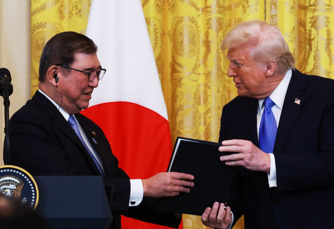 日米首脳会談後の共同記者会見で記念品を手にするドナルド・トランプ大統領(右)と石破茂首相=2025年4月7日、米ワシントン(時事)