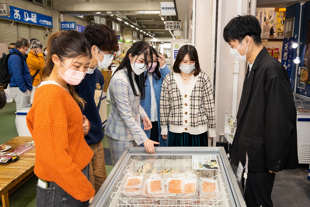 店頭の食材を眺めながら、意見を交わす柴田ゼミの学生たち
