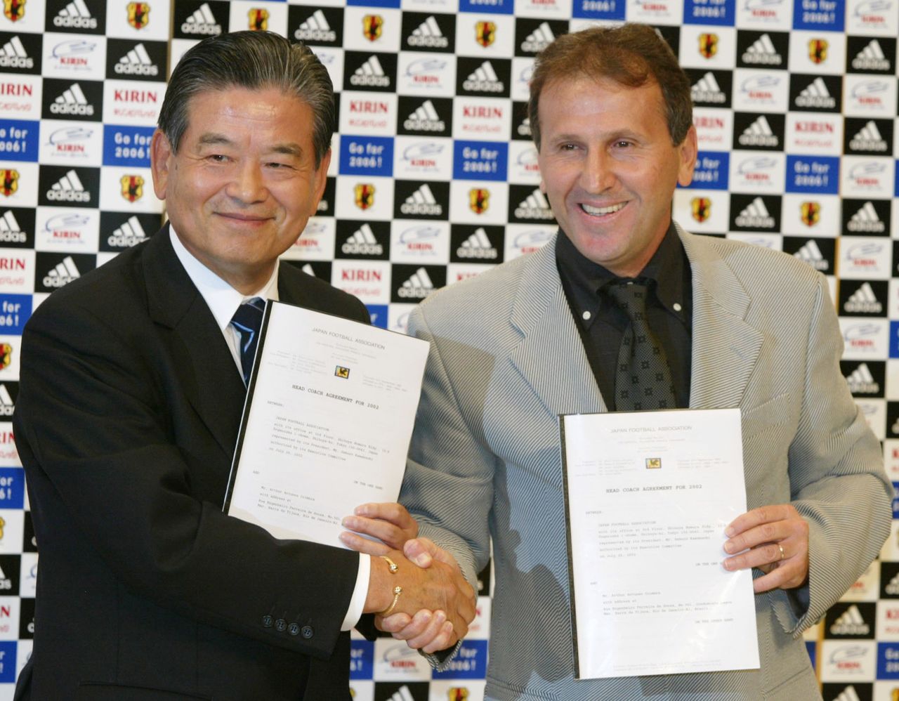 日本代表監督就任会見で川淵三郎日本サッカー協会会長とともに、契約締結書を掲げて握手し、写真撮影に応じるジーコ（2002年7月22日、都内）Reuters