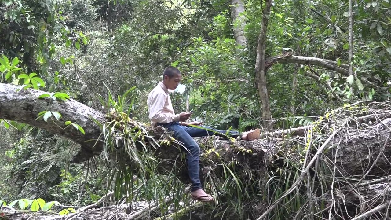 「学校より森がいい」と話すルンくんは、村の人からもらった携帯端末で音楽を楽しむ　©幻視社