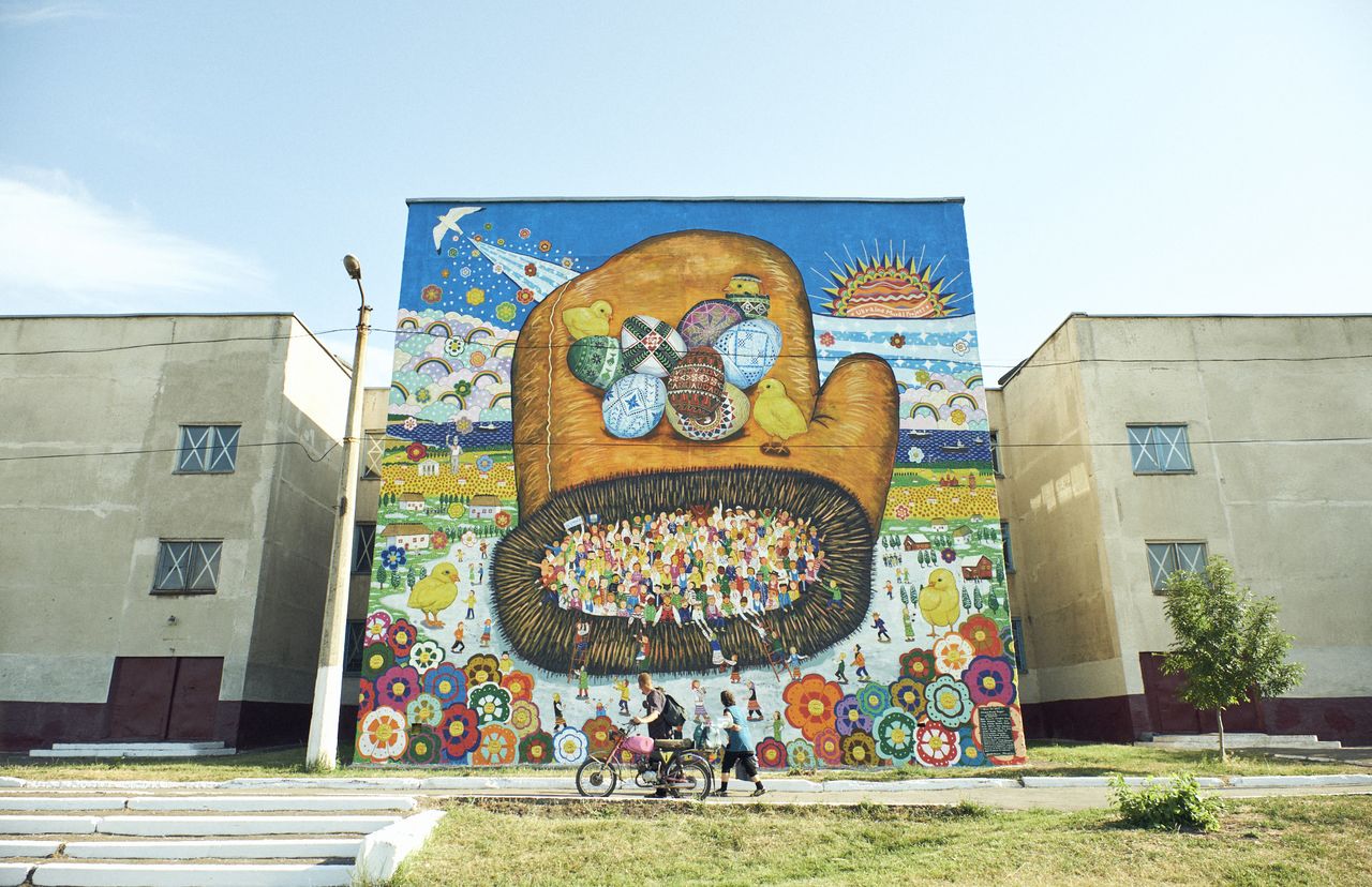 ウクライナ壁画プロジェクト（2017）。2014年の「ウクライナ騒乱」で被弾し、いまだに弾痕が残るマリウポリ市の第68学校の壁に平和のメッセージを込めた壁画を残す　提供：Over the wall